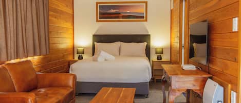Una habitación de hotel con una cama, un escritorio de madera, un sofá de cuero y un televisor.