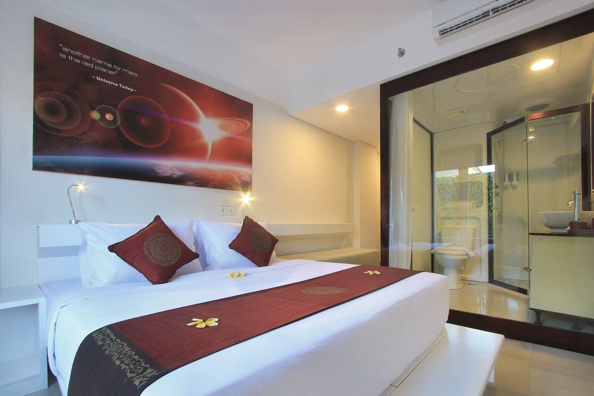 Una habitación de hotel con una cama grande, cabina de ducha de vidrio y un cartel en la pared.