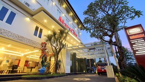 Entrada de hotel con un paseo techado, una estatua y un letrero que indica los servicios del hotel.