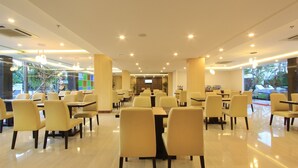 Un amplio comedor interior con varias mesas y sillas, un televisor de pantalla plana y vistas al exterior.
