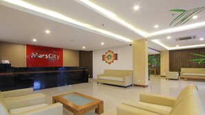 Un vestíbulo de hotel con una recepción, sofás, una mesa de centro y una pared con un emblema circular.
