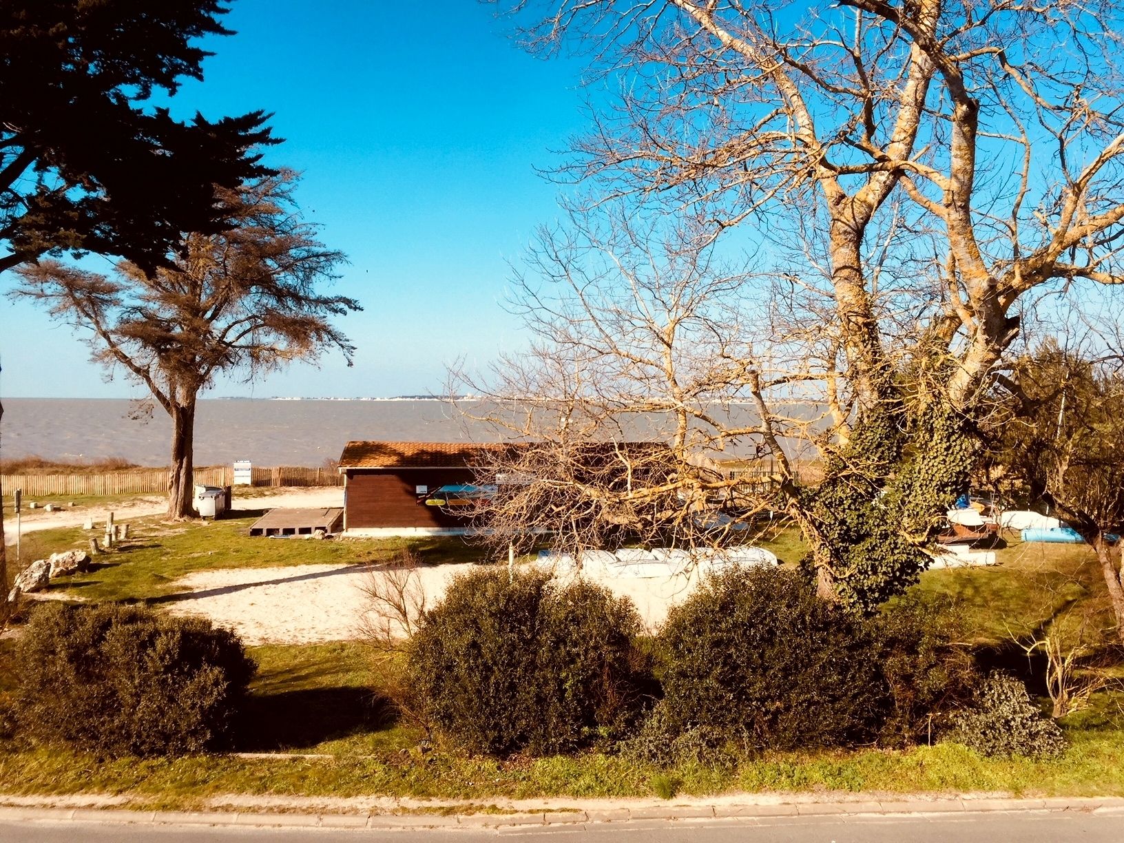 Une propriété située sur la côte, comprenant un grand bâtiment, une zone sablonneuse et une vue sur la mer.