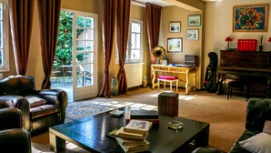 A living room with a piano, a coffee table with books, and a sofa. - Hôtel La Chaloupe (Port-des-Barques)