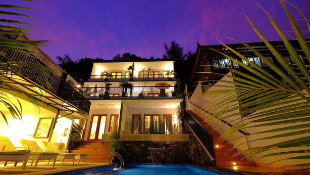 Un edificio de dos pisos con piscina, mobiliario exterior y una escalera que conduce al nivel superior.