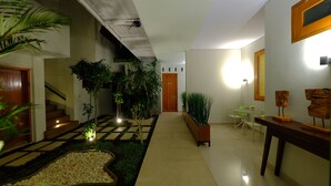 Un interior moderno con suelo a cuadros, una escalera, plantas en macetas y una pequeña mesa con sillas.