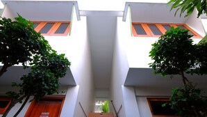 Una escalera conduce a un segundo piso con un letrero que dice 'Staff Only', bordeada por árboles y edificios con paredes blancas y puertas de madera.