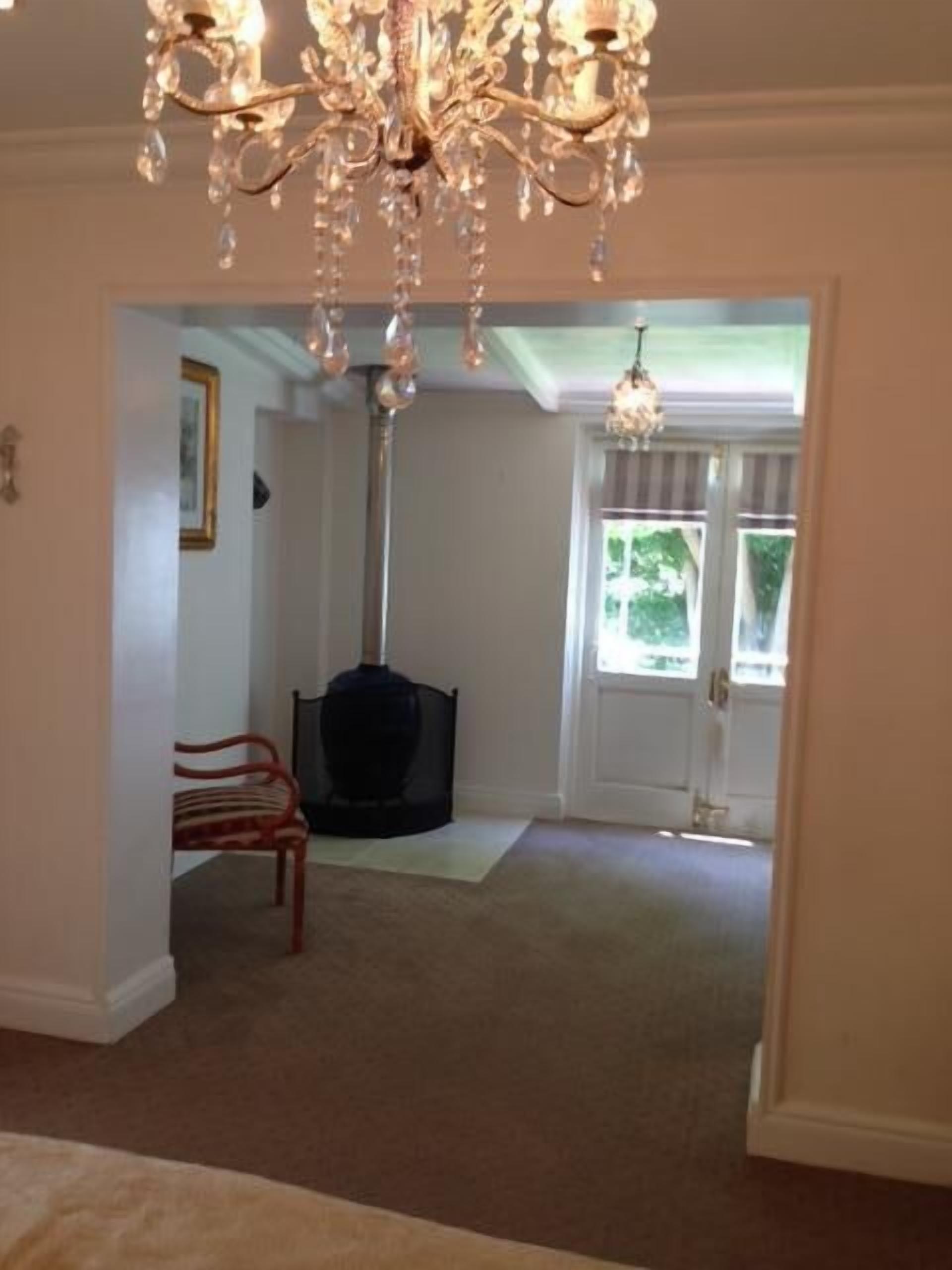 A spacious living room with a large chandelier, a fireplace, and a door leading outside.