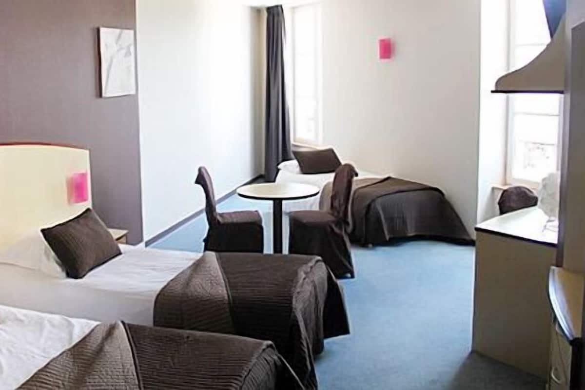 Une chambre d’hôtel avec deux lits, une petite table et une chaise.