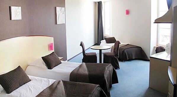 A hotel room with two beds, a small table, and a chair.