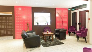 A modern lounge area with leather sofas, a wooden coffee table, and a red patterned wall. - Hôtel de France (Montmorillon)