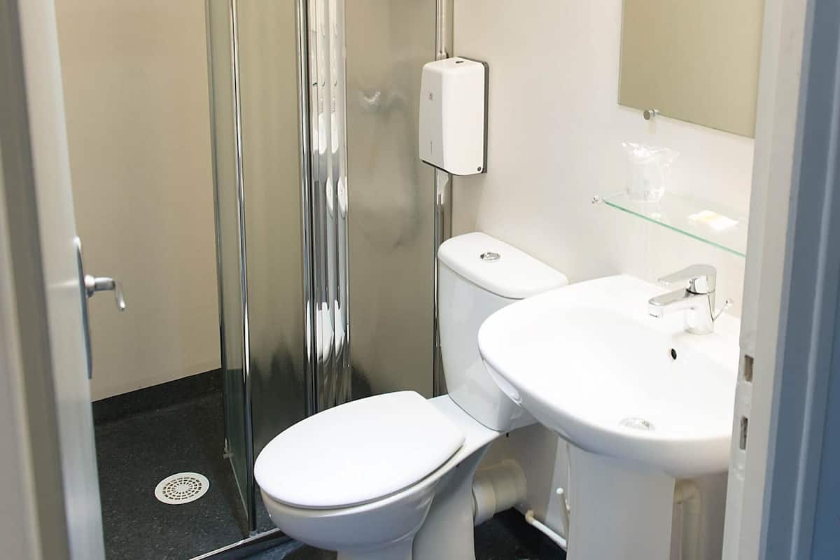 Une salle de bain avec une douche à parois de verre, des toilettes blanches et un lavabo avec un miroir au-dessus.