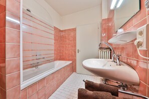 A bathroom with a bathtub, a sink, and a mirror. - HOTEL Bar des VOSGES (Munster)