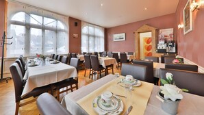 A dining area with tables set for service, large windows, and a view of the city. - HOTEL Bar des VOSGES (Munster)