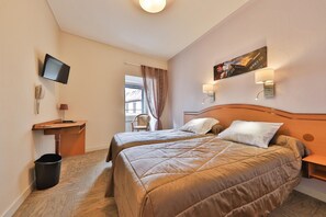 A hotel room with two beds, a desk, a chair, a TV, and a painting on the wall. - HOTEL Bar des VOSGES (Munster)