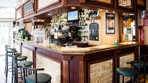 A bar area with a counter, stools, and a television screen. - HOTEL Bar des VOSGES (Munster)