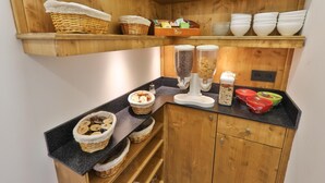 A kitchen with wooden shelves, baskets, and a coffee machine. - HOTEL Bar des VOSGES (Munster)