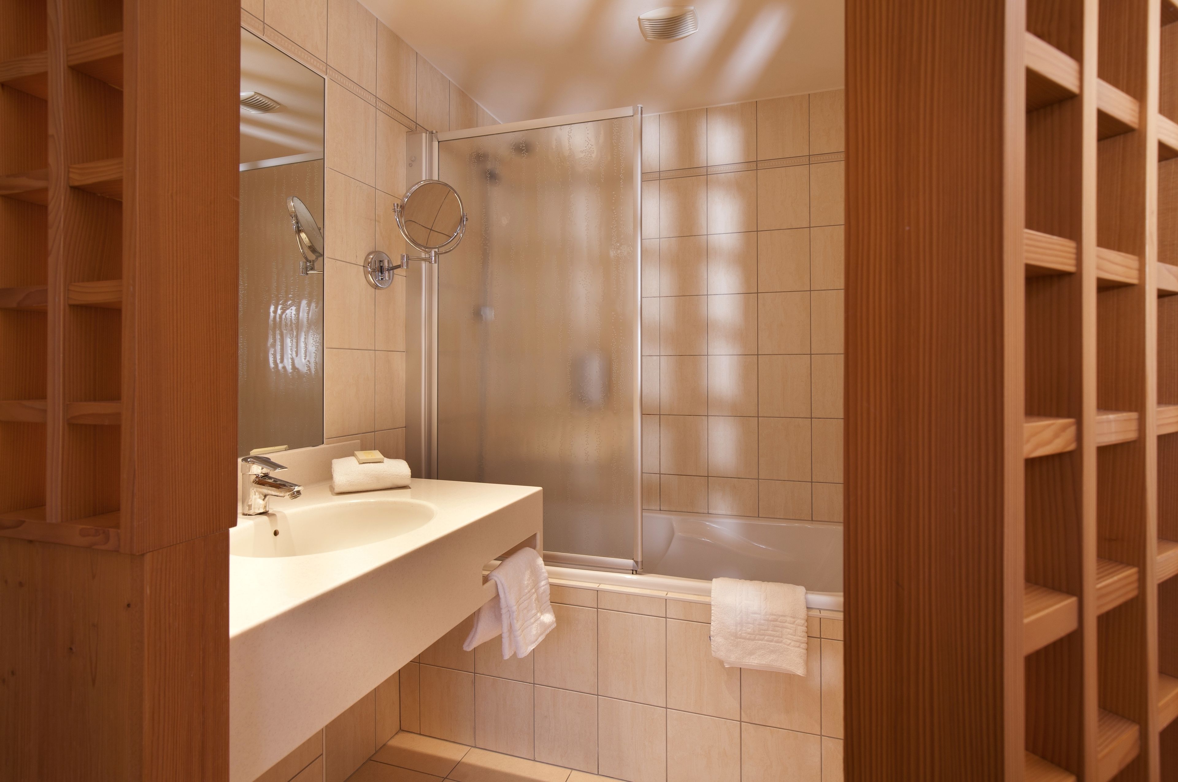 A modern bathroom with a shower, a sink, and a mirror.
