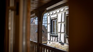Blick durch eine Holzbalustrade auf ein traditionelles Gebäude mit freiliegenden Holzbalken und einem Ziegeldach.