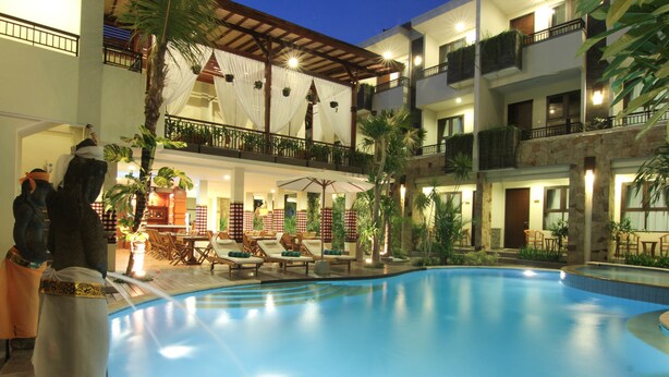 A hotel with a swimming pool, lounge chairs, and a covered outdoor seating area. - Manggar Indonesia Hotel & Residence (Kuta)