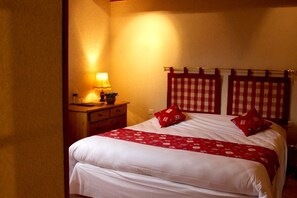A hotel room with a bed, a nightstand, a lamp, and a checkered headboard. - Auberge du Brand (Turckheim)