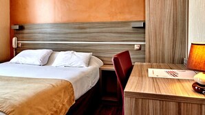 A hotel room with a bed, a desk, a chair, and a lamp. - Logis Hotel Au Relais Nivernais (Nevers)