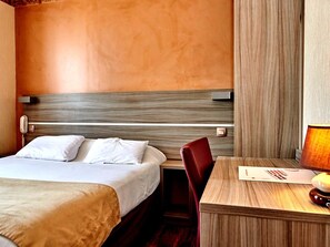 A hotel room with a bed, a desk, a chair, and a lamp. - Logis Hotel Au Relais Nivernais (Nevers)