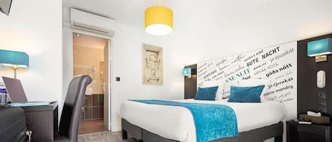 Ein modernes Hotelzimmer mit Bett, Schreibtisch, Stuhl und einer Wand mit Text.