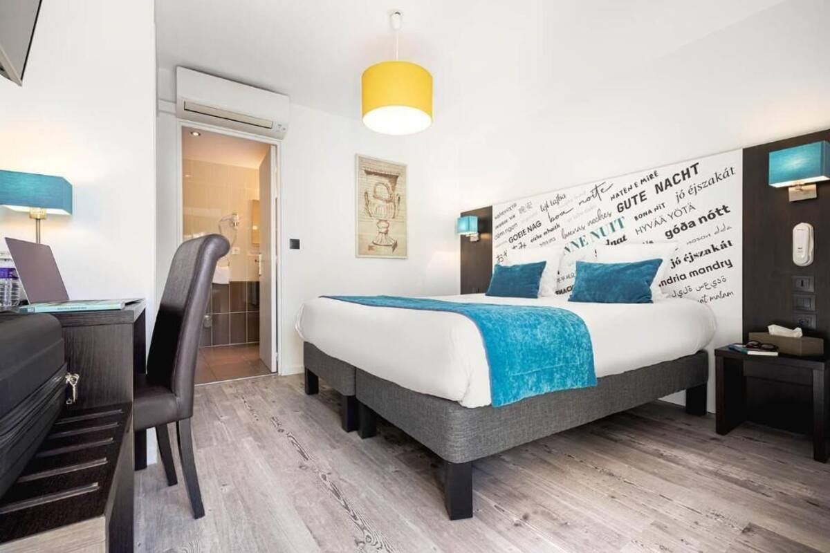 A modern hotel room with a bed, desk, chair, and a wall with text.