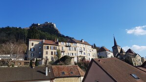 A historic town with a prominent castle on a hill, traditional buildings with balconies, and a church with a tall spire.
