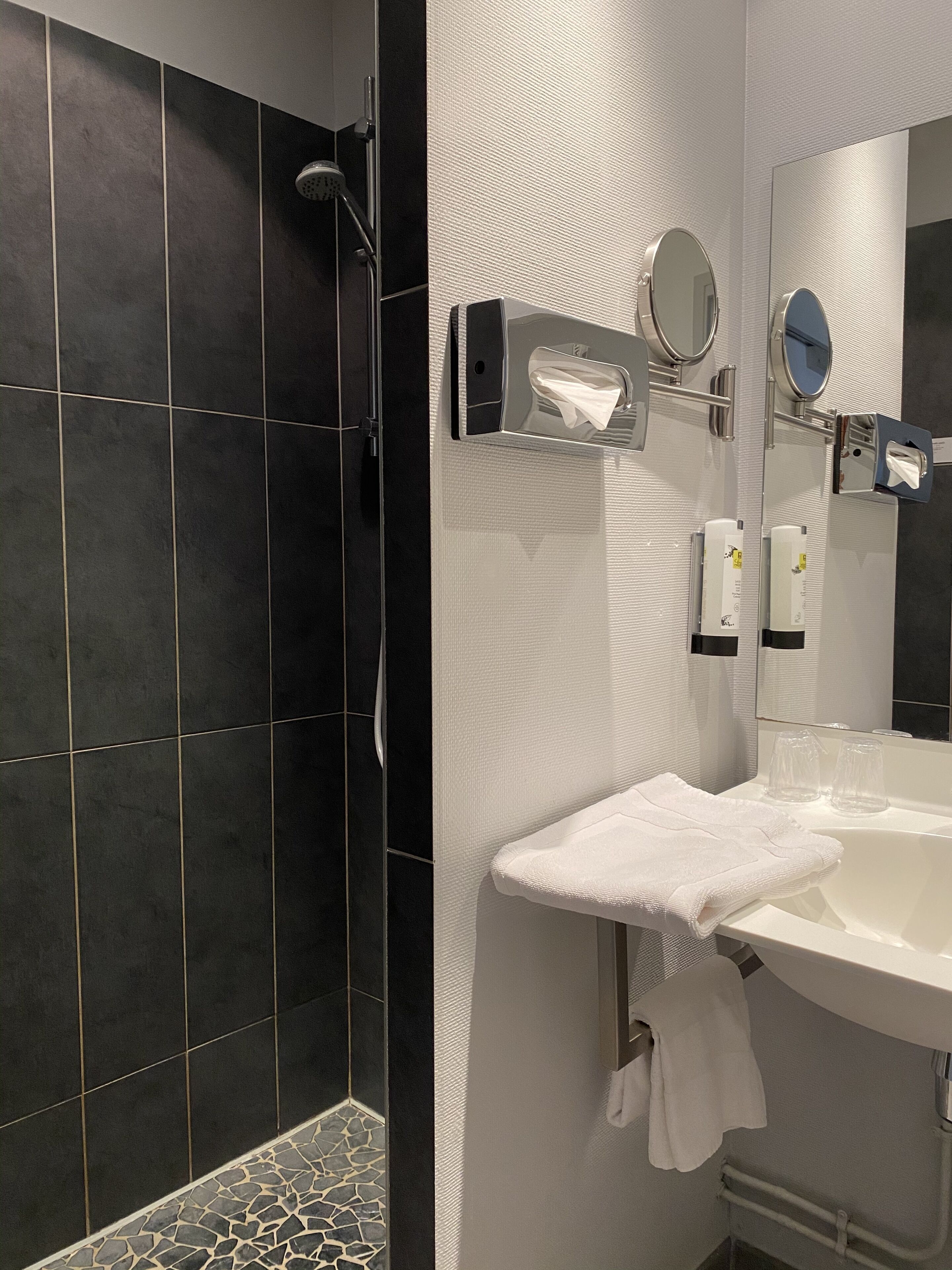 Un baño moderno con ducha, lavabo con espejo y perchero.