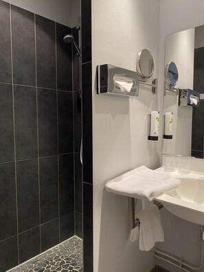 Un baño moderno con ducha, lavabo con espejo y perchero.