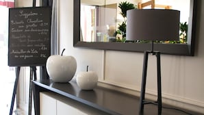 A modern interior with a black-framed mirror, a chalkboard menu, and two white decorative objects on a black countertop. - Hôtel CARRER Le Rhien (Ronchamp)