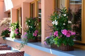 A row of outdoor seating with wicker planters containing flowers. - Hôtel CARRER Le Rhien (Ronchamp)