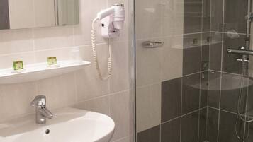 Une salle de bain équipée d’un lavabo, d’un miroir et d’une douche avec une porte en verre.