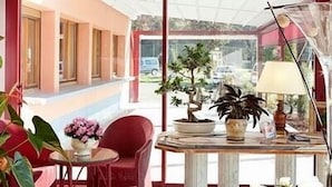 A room with a red chair, a small round table, a potted plant, and a lamp. - Hôtel CARRER Le Rhien (Ronchamp)