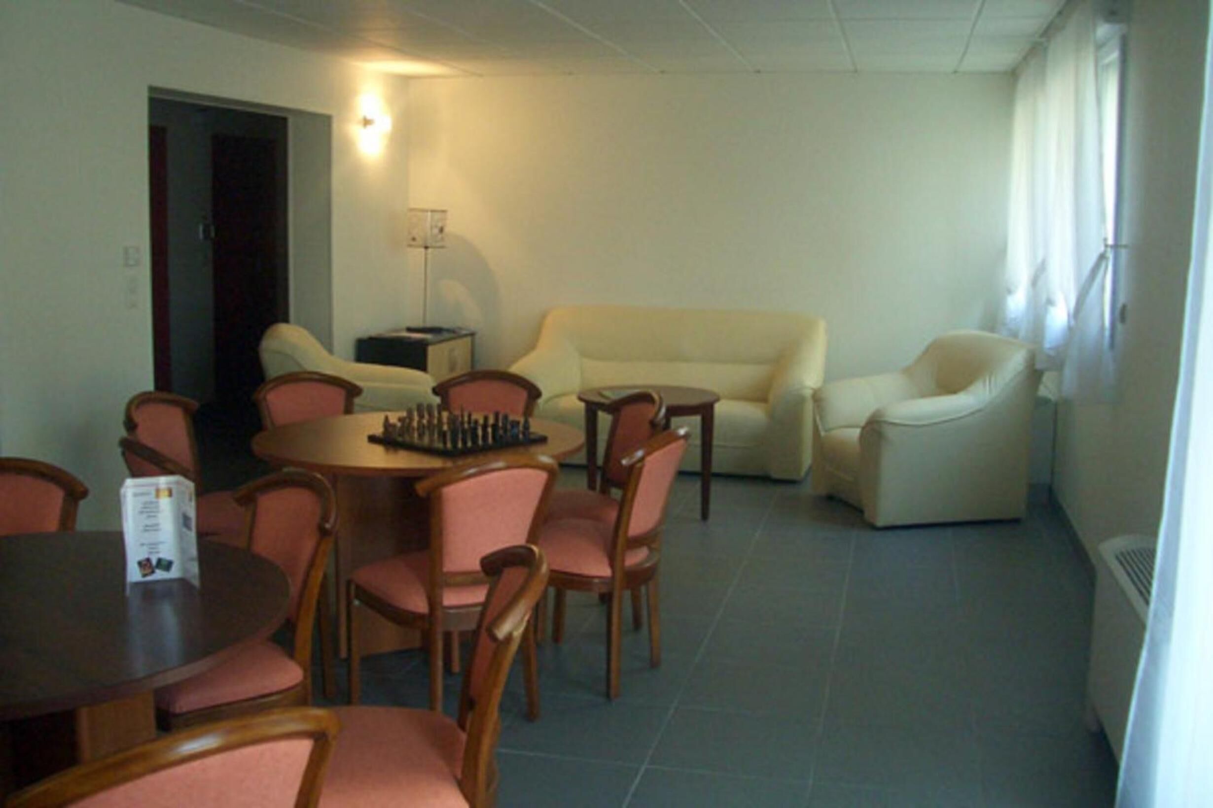 A dining area with a round table and chairs, a sofa, and a lamp.