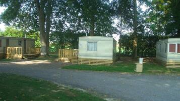 Une rangée de maisons mobiles dotées de terrasses en bois, séparées par un chemin pavé.