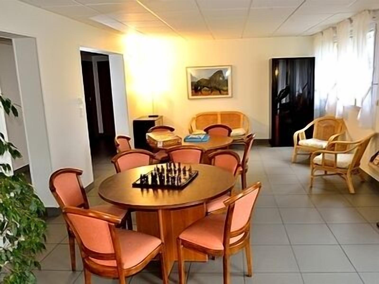A dining area with a round table, chairs, and a chessboard.