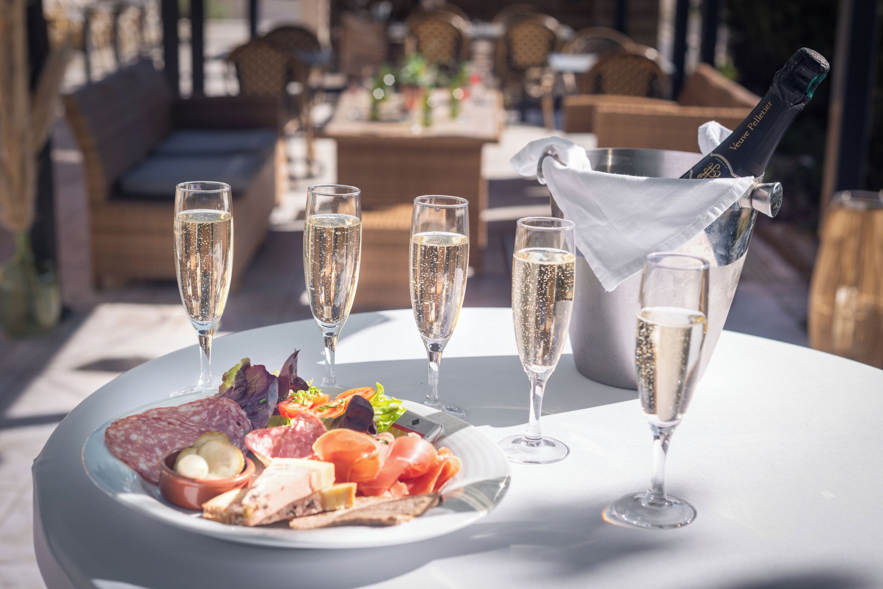 A table with a plate of food, glasses of champagne, and a bottle of champagne.