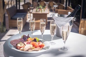 A table with a plate of food, glasses of champagne, and a bottle of champagne. - Hôtel Le Relais du Parisis (Villeparisis)