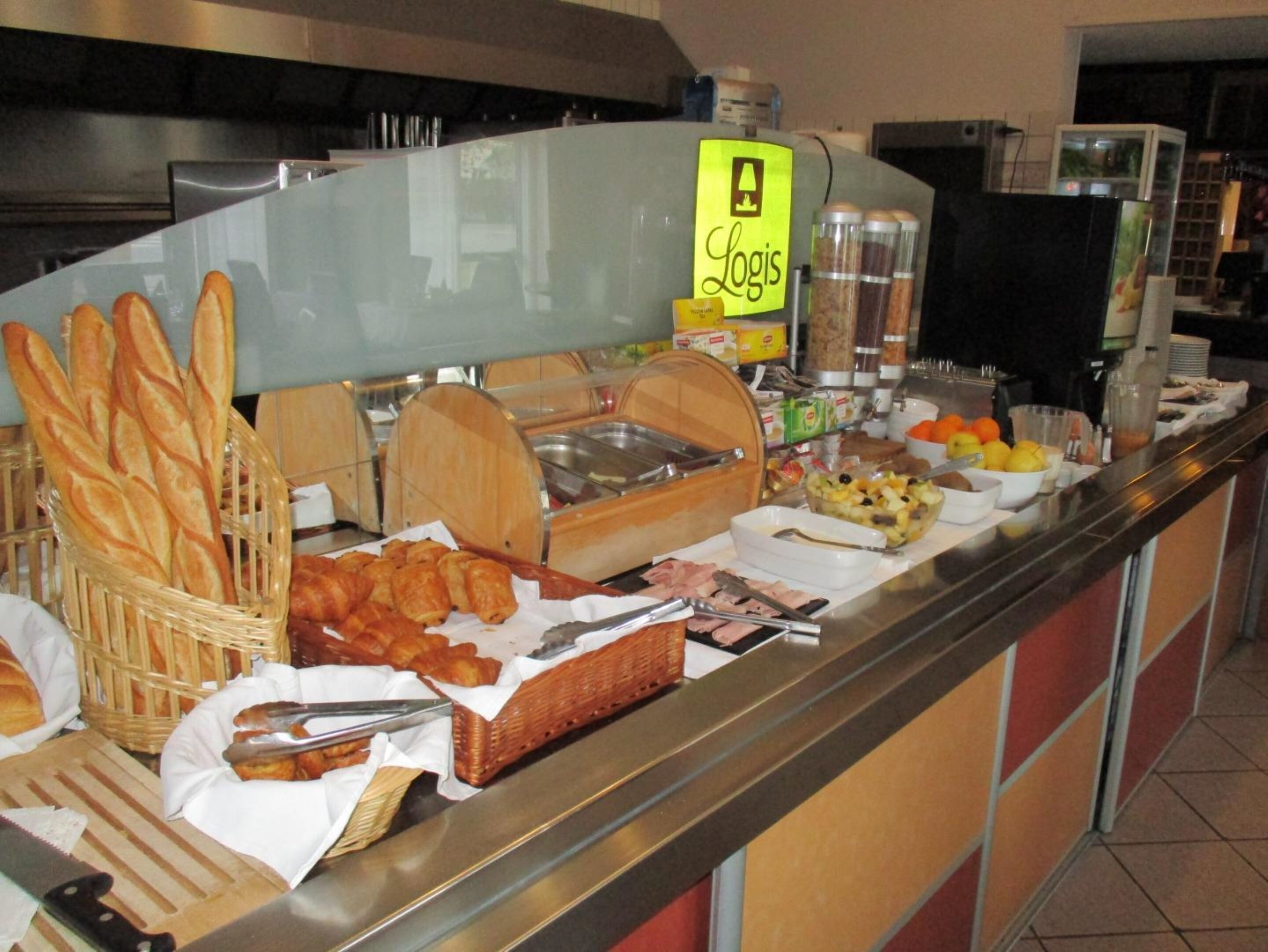 A buffet with various food items, including bread, pastries, and fruits.