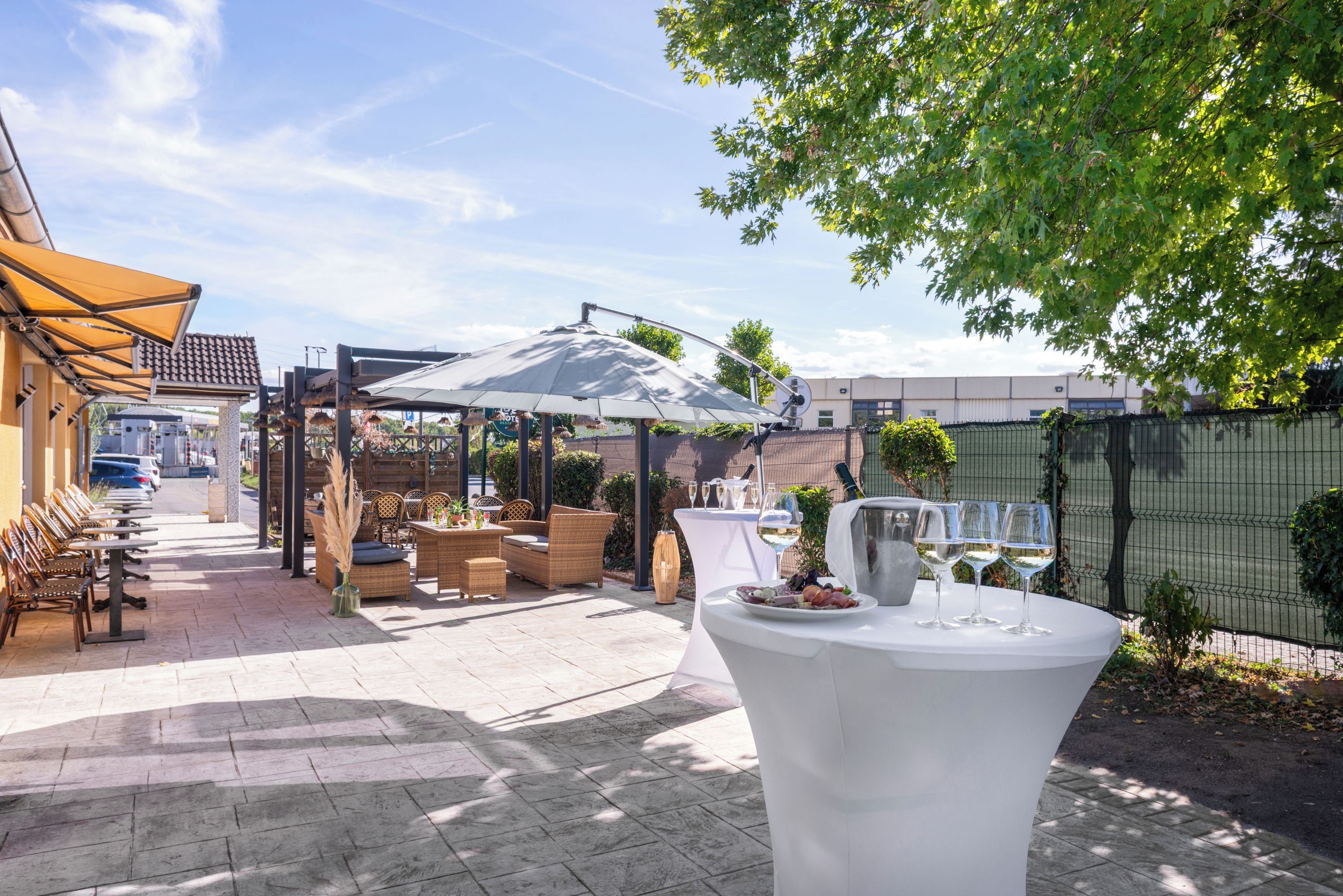 An outdoor patio area with tables and chairs, a covered seating area, and a fence.