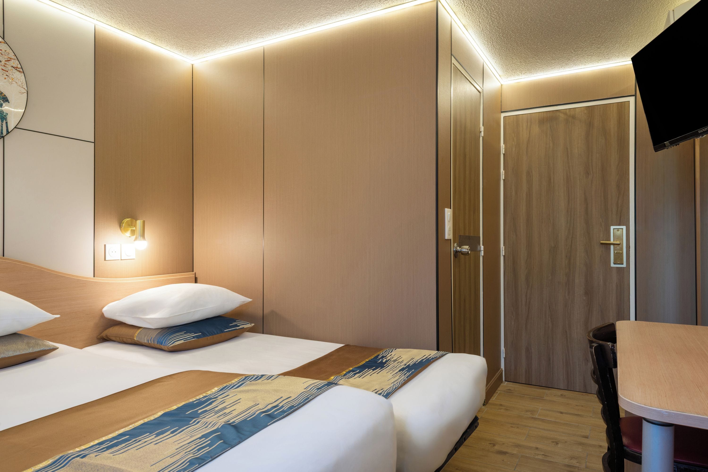 Une chambre d’hôtel équipée d’un lit, d’une table de chevet et d’un téléviseur fixé au mur.