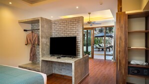 Una habitación moderna con televisor en una pared de piedra, un perchero y un estante de madera con toallas.