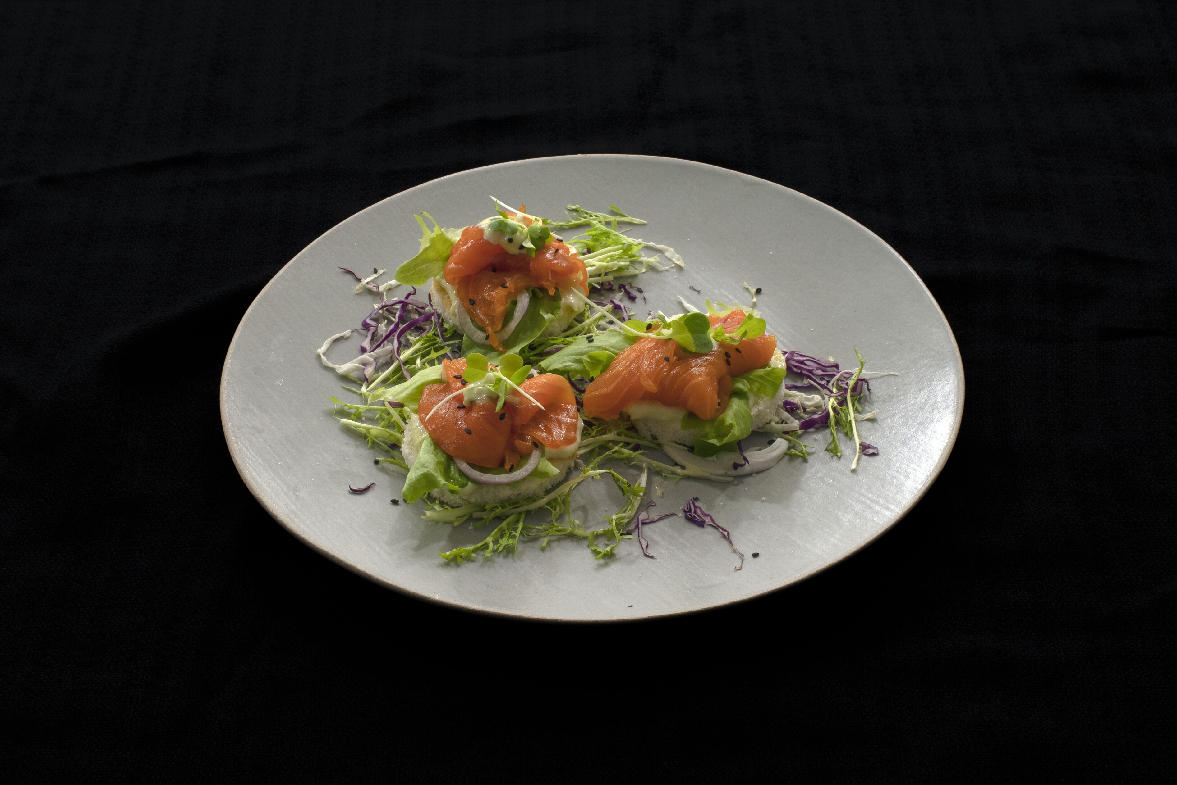 A plate of food with salmon and greens on a dark background.