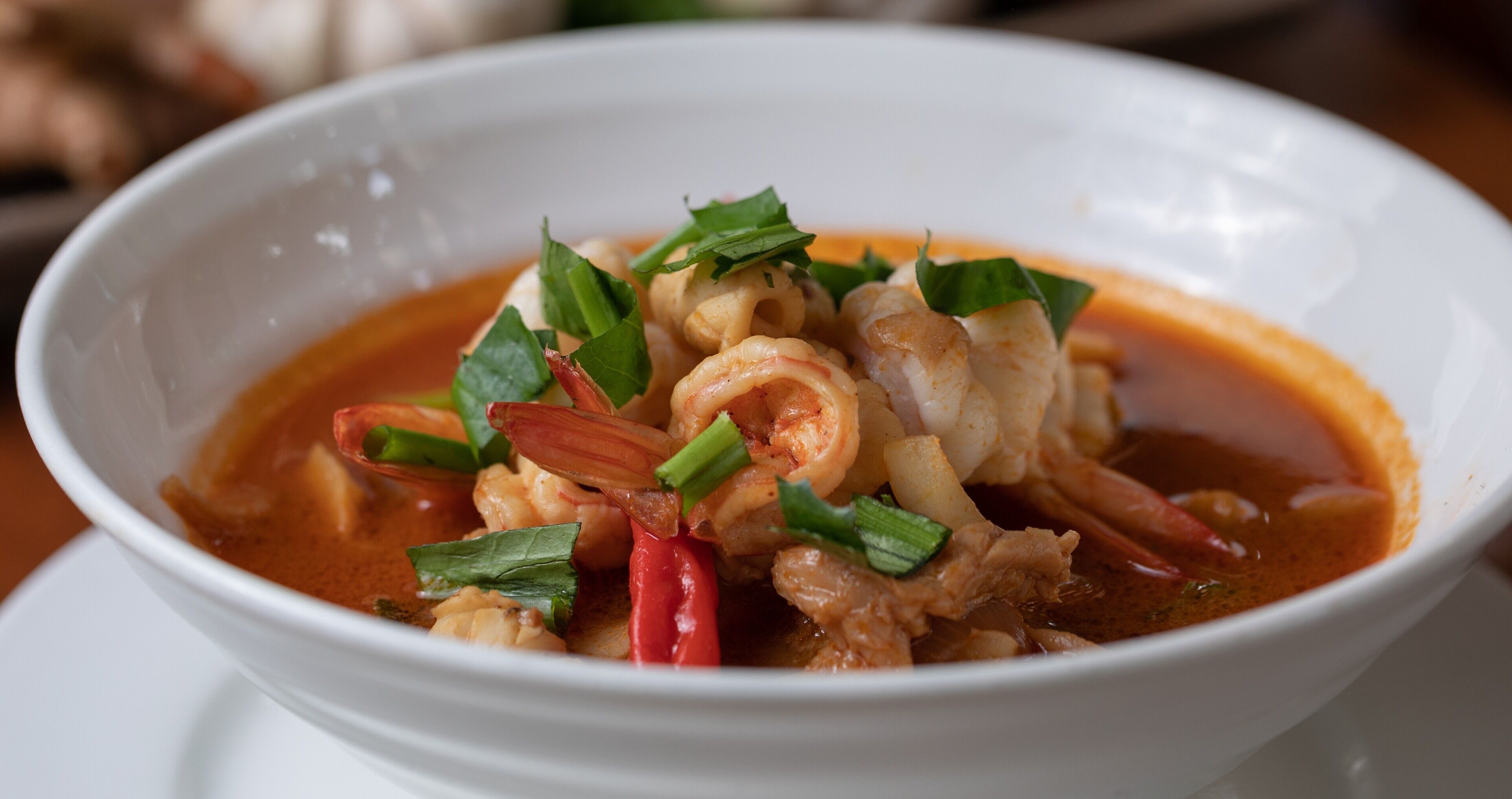 Eine Schüssel Suppe mit Garnelen und Gemüse.