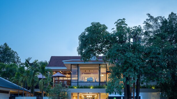 A modern two-story house with a balcony, large windows, and a well-lit entrance.