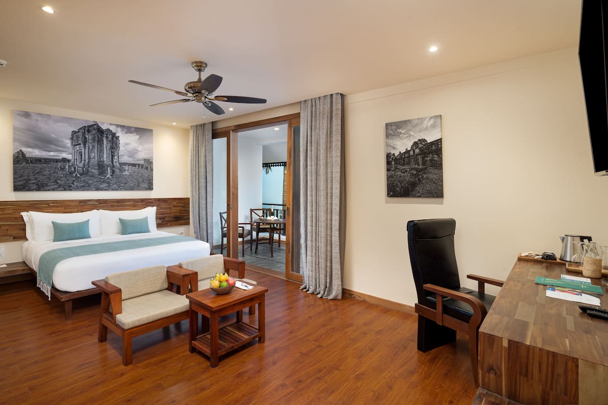 Une chambre d’hôtel avec un grand lit, des meubles en bois, un bureau et des œuvres d’art accrochées aux murs.