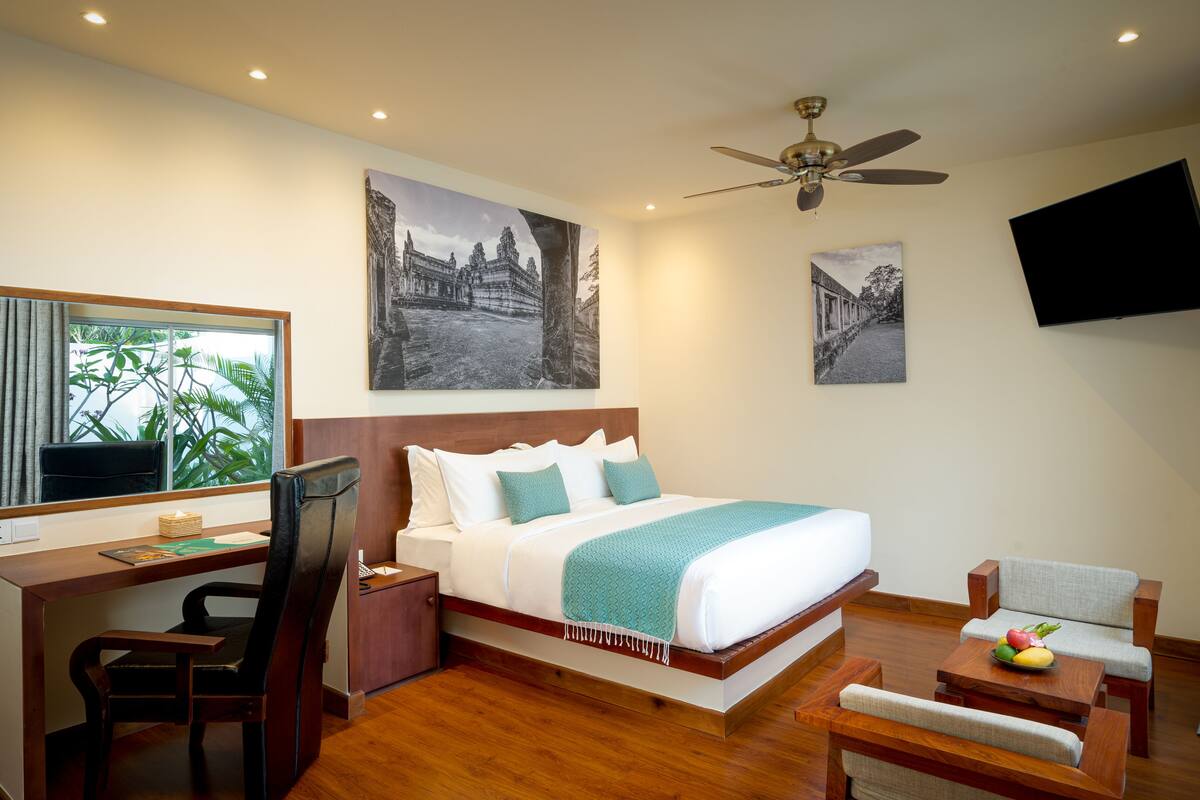 Une chambre d’hôtel équipée d’un lit, d’un bureau, d’une chaise et d’un téléviseur fixé au mur.