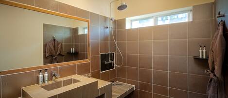 A modern bathroom with a large mirror, dual sinks, a shower, and a towel rack.